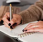 Une femme qui écrit sur un carnet préparant un site internet